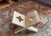 Load image into Gallery viewer, Decorative wooden book with intricate designs on a patterned rug