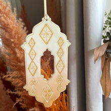 Load image into Gallery viewer, Decorative hanging mirror with gold geometric patterns in a home setting.