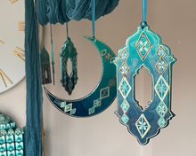 Load image into Gallery viewer, Decorative Ramadan table setting with teal and gold elements, including a clock and hanging decorations.